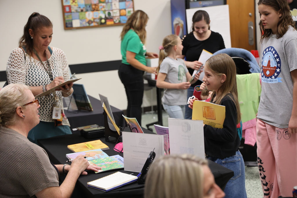 An Indianapolis school principal and elementary educators smiling and interacting with magician Jamahl Keyes at a school community night event.